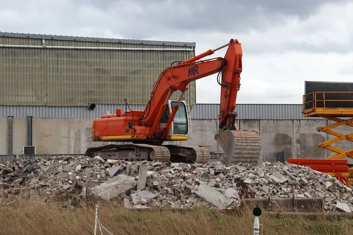 Excavator beside a pile of demolition rubble